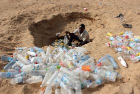 Mann am Strand mit Plastikflaschen